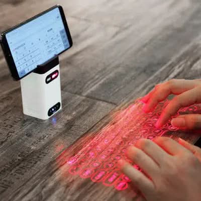 Clavier laser virtuel projeté sur une surface avec mains en train de taper à côté d'un appareil blanc
